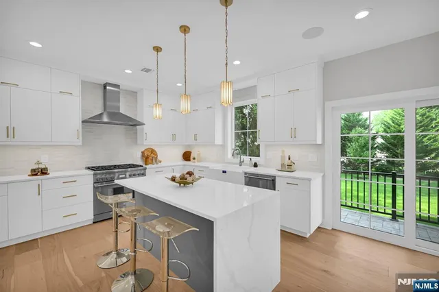 a kitchen with stainless steel appliances a stove a sink a center island and a wooden floor