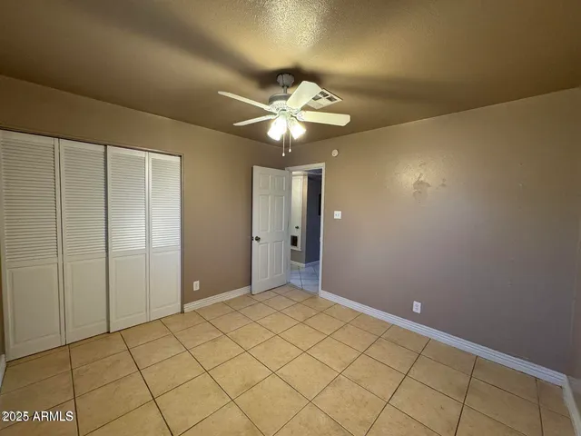 a view of an empty room and chandelier fan