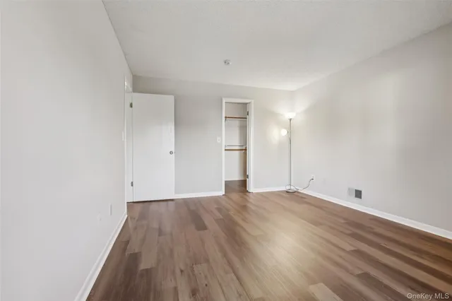 a view of an empty room with wooden floor and window