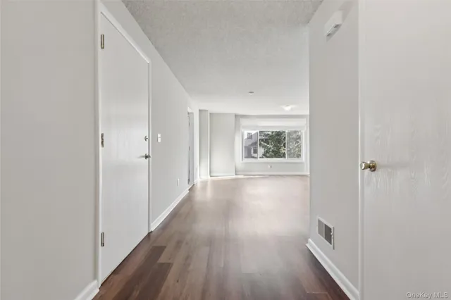 a view of a hallway with wooden floor and closet