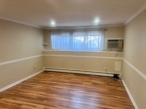 a view of an empty room with a window and wooden floor