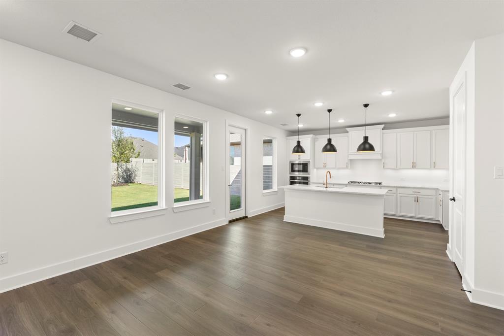 4100 Explorer Way McKinney, TX 75071 - Photo 9 of 27 a large white kitchen with kitchen island a sink wooden floor and a large window