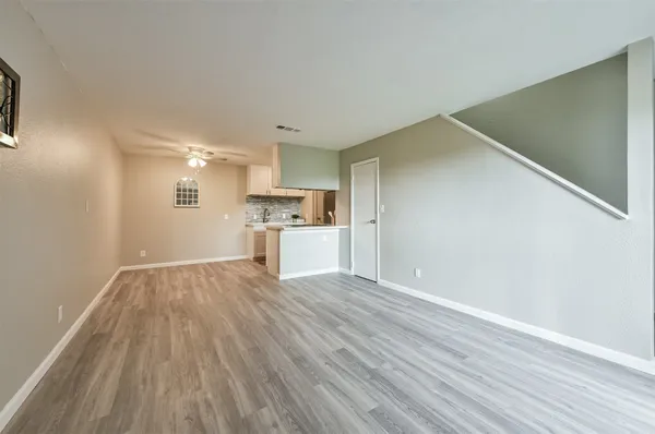 a view of a kitchen with wooden floor electronic appliances and stairs