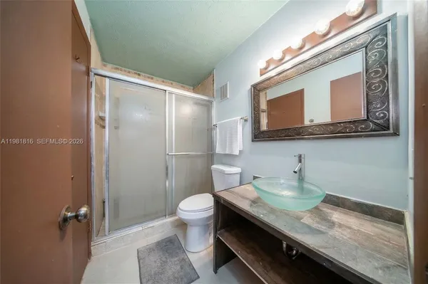 a bathroom with a granite countertop sink a toilet and shower