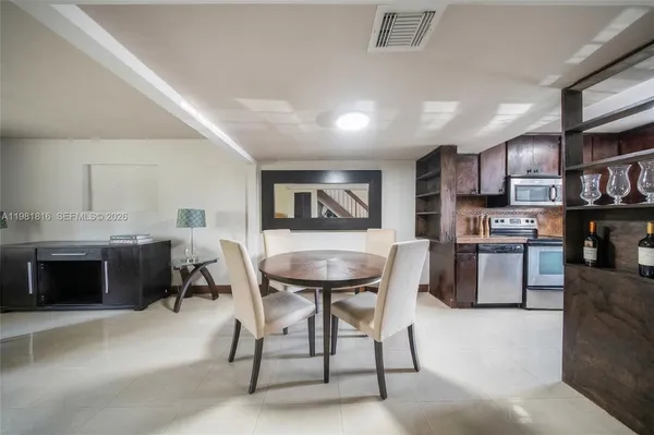 a kitchen with stainless steel appliances kitchen island granite countertop a table chairs sink and stove