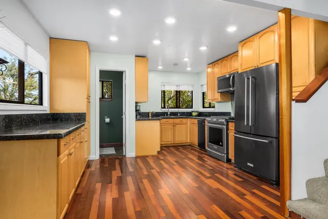 a kitchen with stainless steel appliances granite countertop a refrigerator a sink and a stove