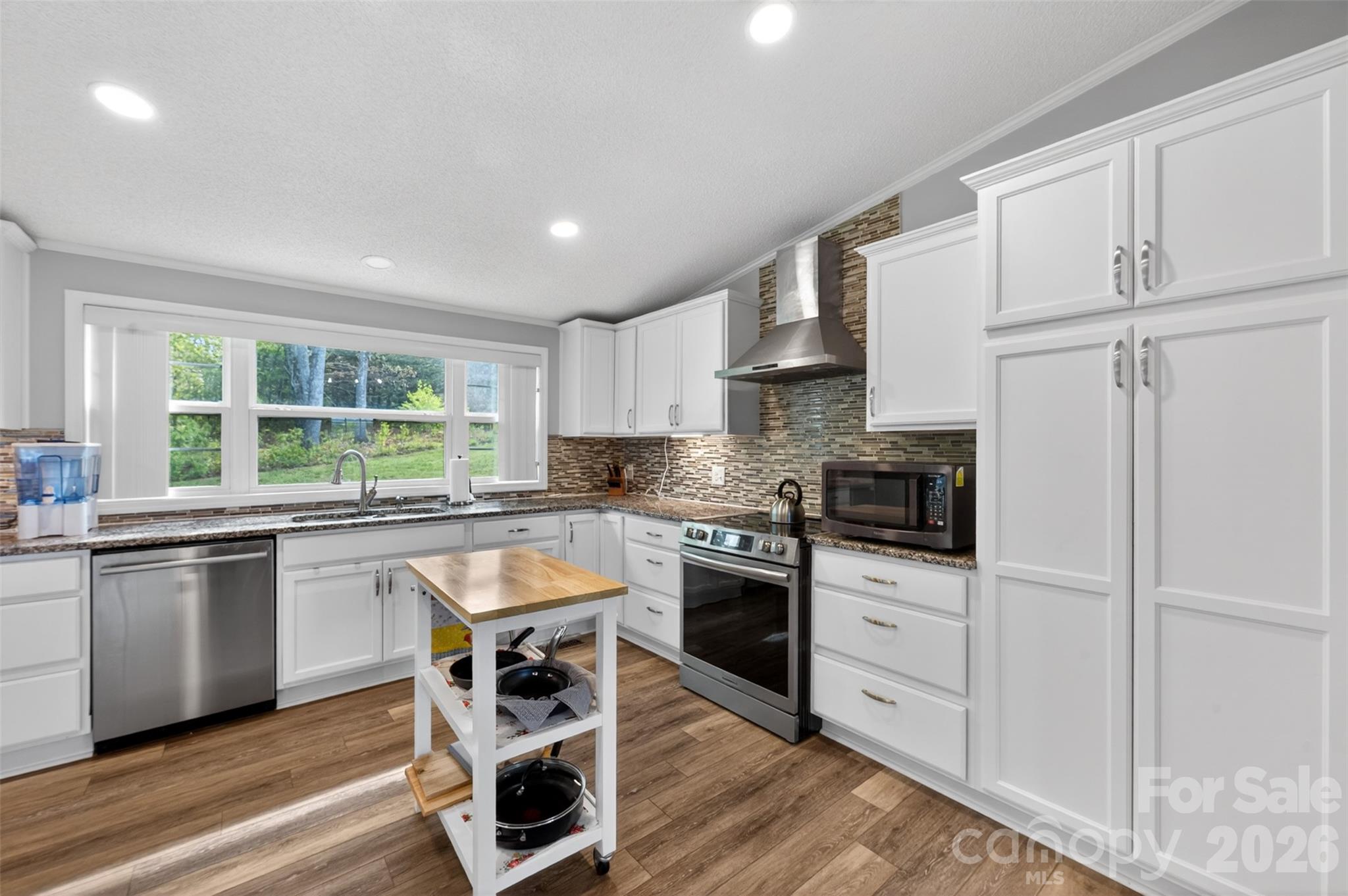 4352 Anderson Mountain Road Maiden, NC 28650 - Photo 15 of 42 a kitchen with stainless steel appliances granite countertop a stove top oven a sink dishwasher and white cabinets with wooden floor