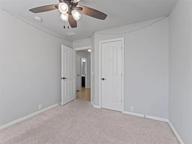 a view of an empty room and chandelier fan