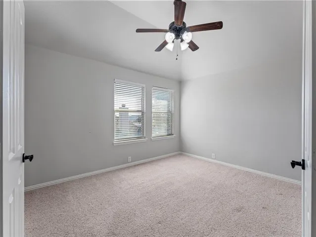 an empty room with a chandelier fan and windows