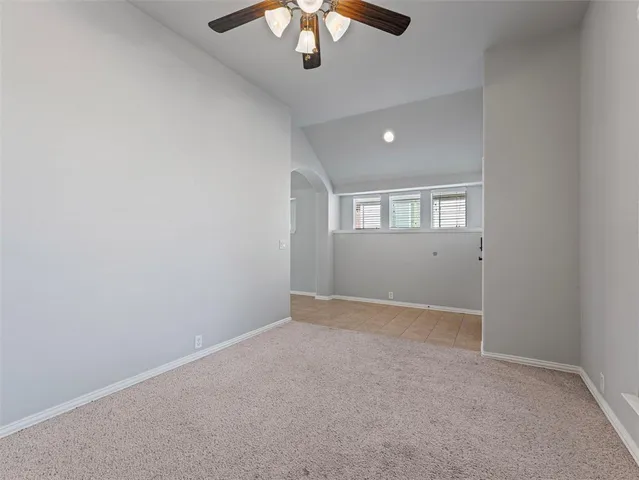 an empty room with a chandelier fan and windows
