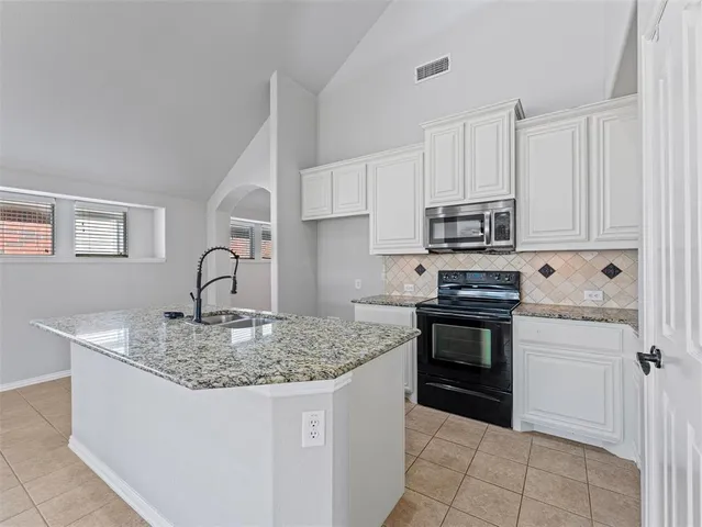 a kitchen with kitchen island granite countertop a stove sink and microwave
