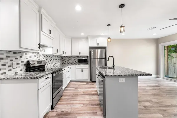 a kitchen with granite countertop a sink stainless steel appliances and white cabinets