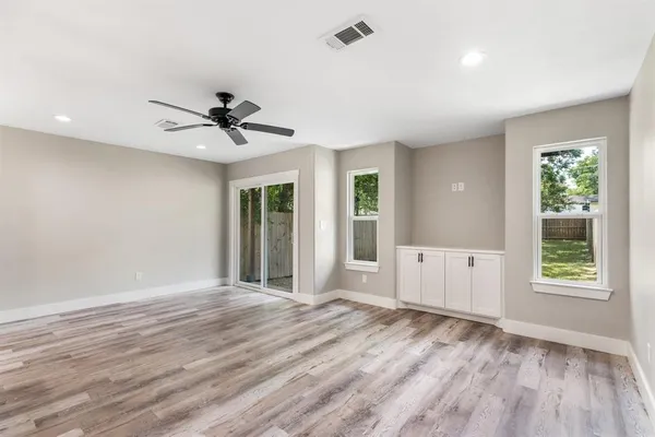 a view of an empty room with a window and wooden floor