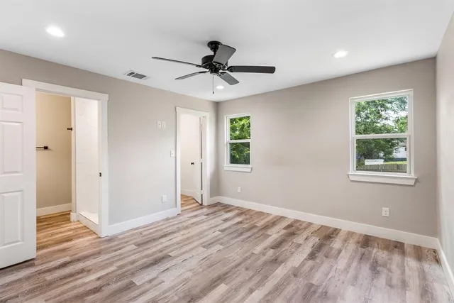 a view of empty room with wooden floor and fan
