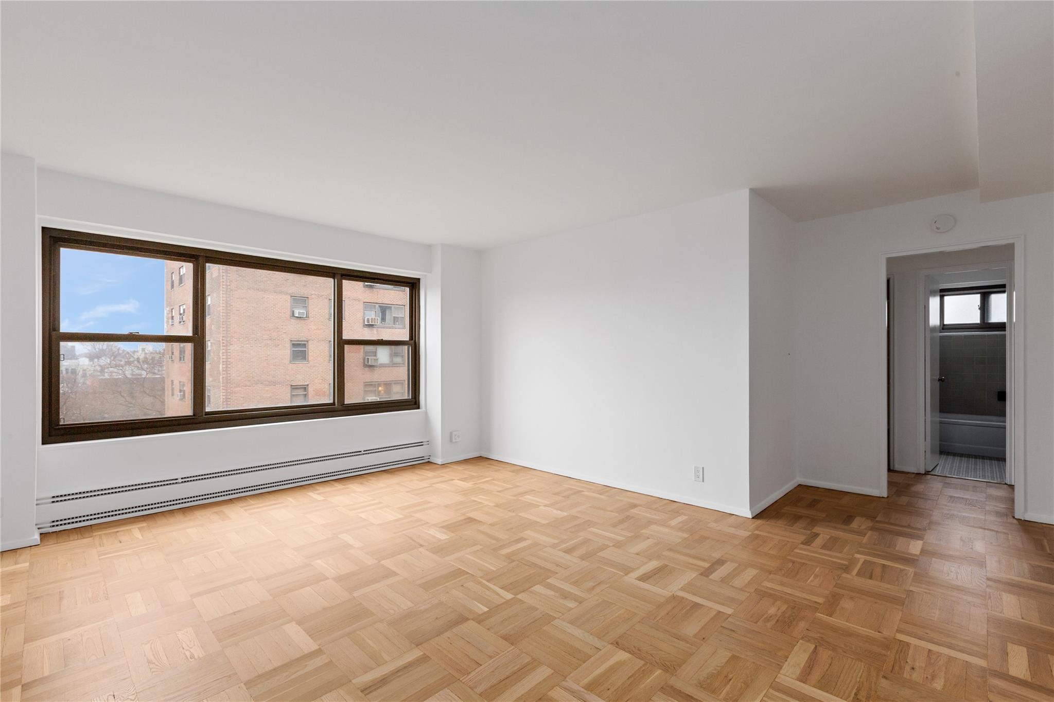 21-80 33rd Road, Unit 7D Queens, NY 11106 - Photo 3 of 12 a view of an empty room with window and wooden floor