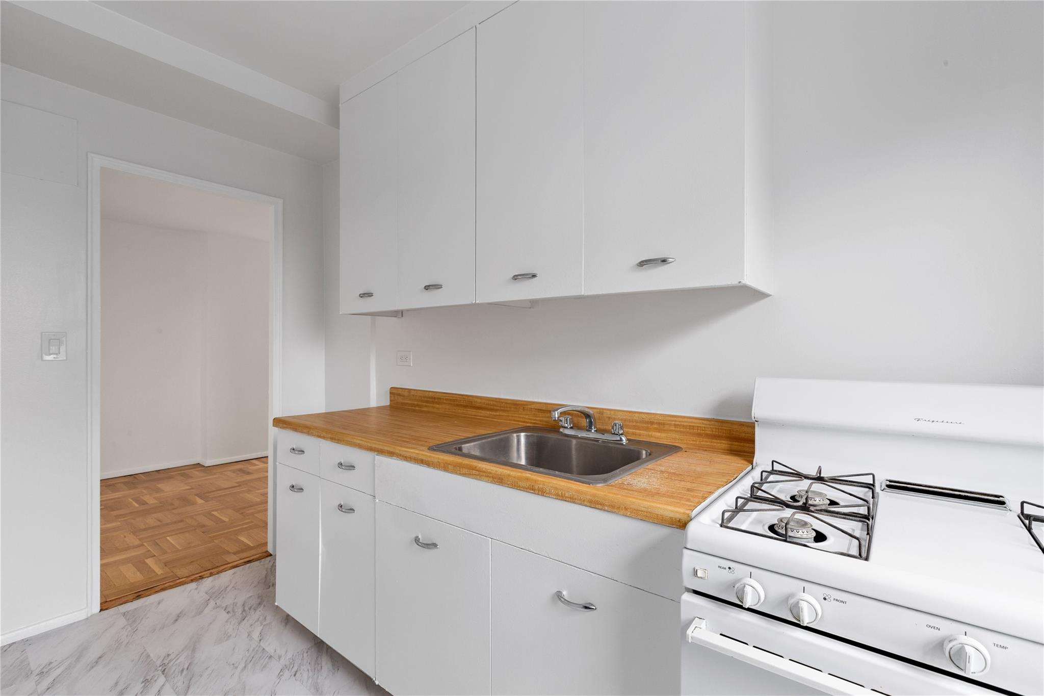 21-80 33rd Road, Unit 7D Queens, NY 11106 - Photo 5 of 12 a kitchen with white cabinets and white appliances