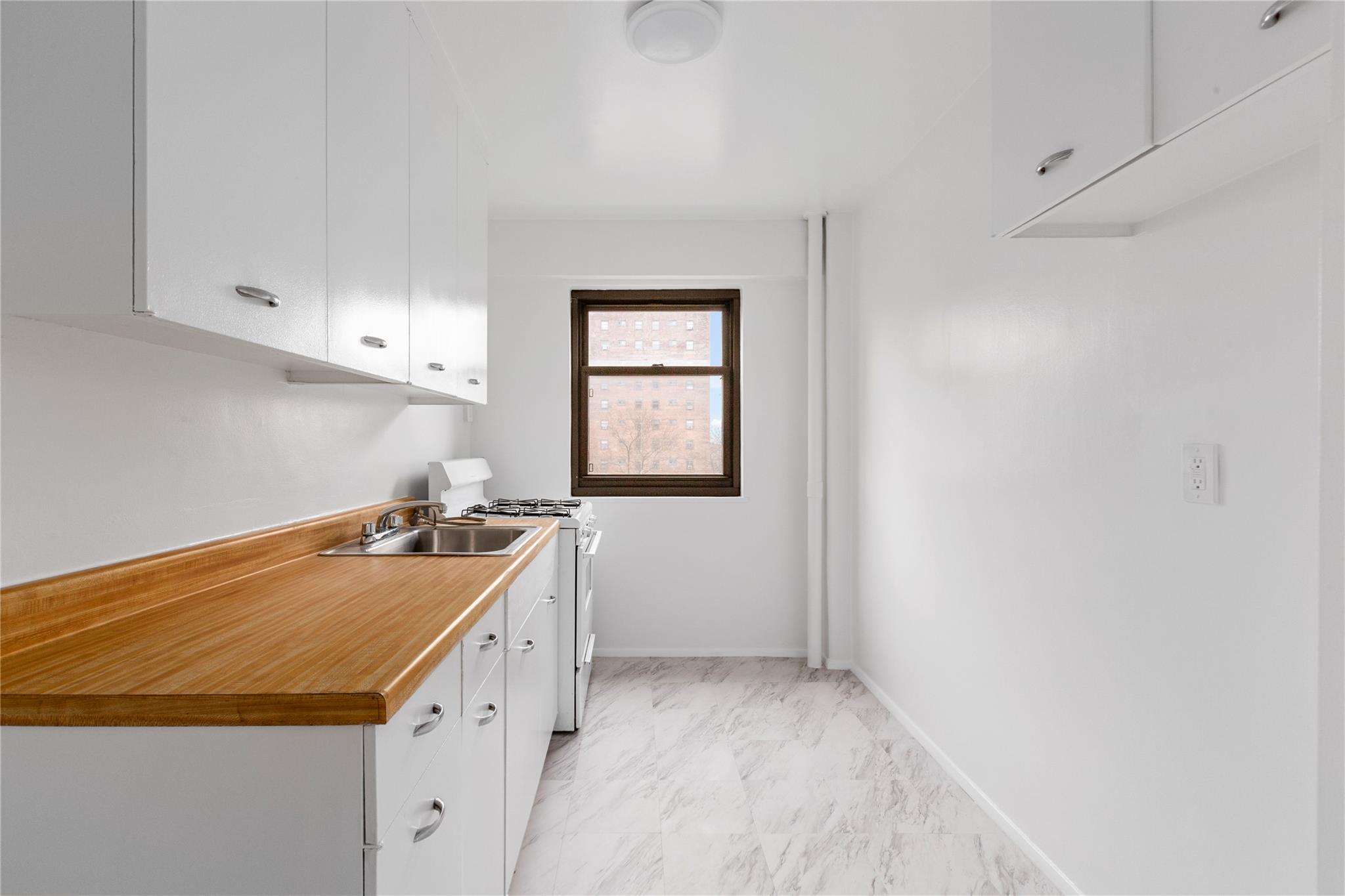 21-80 33rd Road, Unit 7D Queens, NY 11106 - Photo 6 of 12 a room with a stove a sink and a window