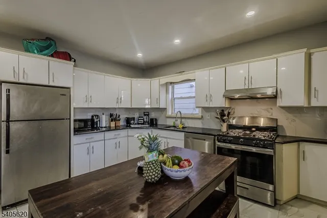 a kitchen with stainless steel appliances granite countertop a refrigerator sink and stove