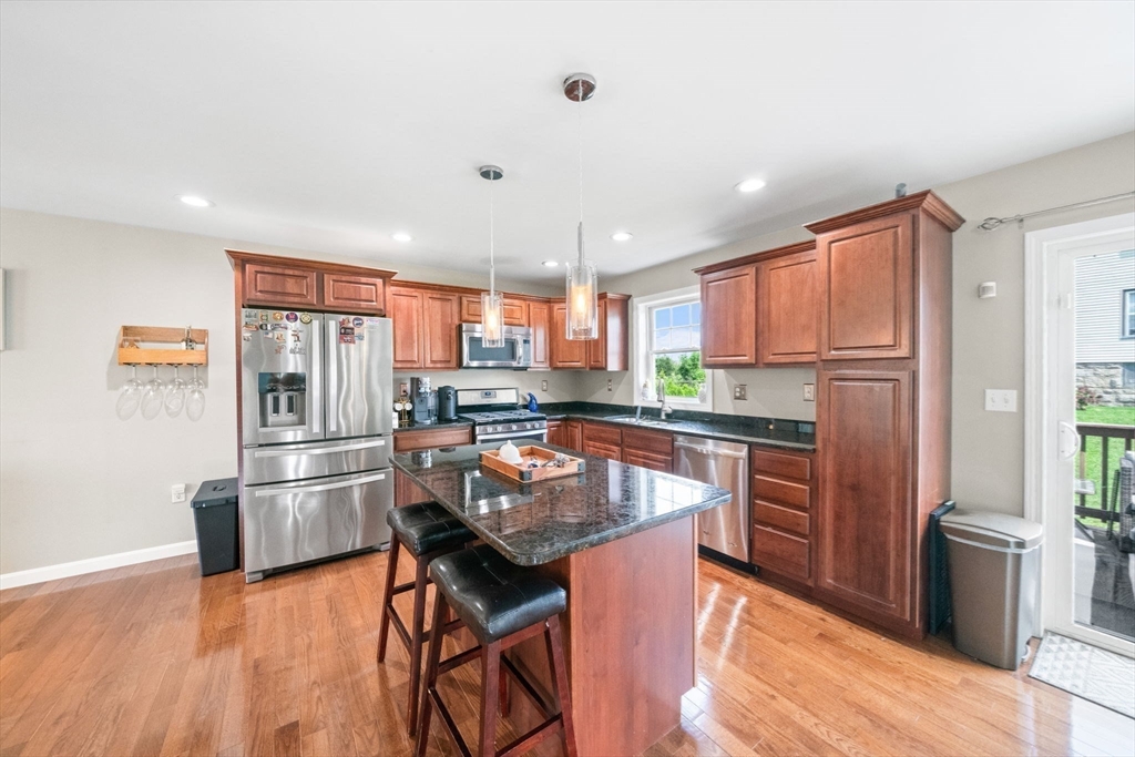 38 Renaud Street Fall River, MA 02721 - Photo 8 of 25 a kitchen with stainless steel appliances granite countertop a refrigerator a stove top oven a sink dishwasher and wooden cabinets with wooden floor