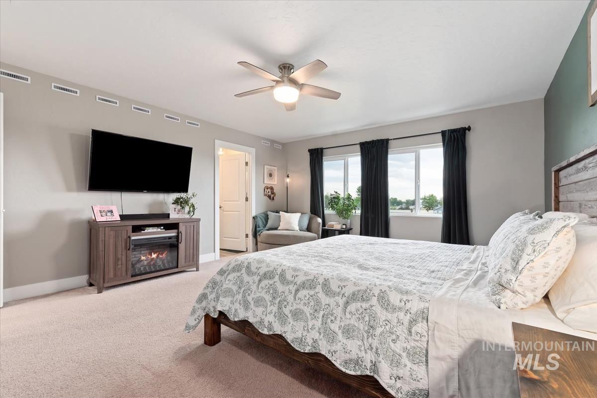 815 Knowledge Street Middleton, ID 83644 - Photo 26 of 49 Spacious bedroom featuring light-colored carpeting, multiple windows with dark drapery, and a ceiling fan with integrated lighting