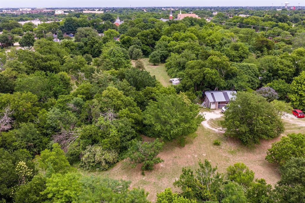 1007 West Belt Line Road Cedar Hill, TX 75104 - Photo 14 of 30 Expansive treed parcel featuring a rustic structure with a metal roof and wood siding, surrounded by mature trees and open grassy areas