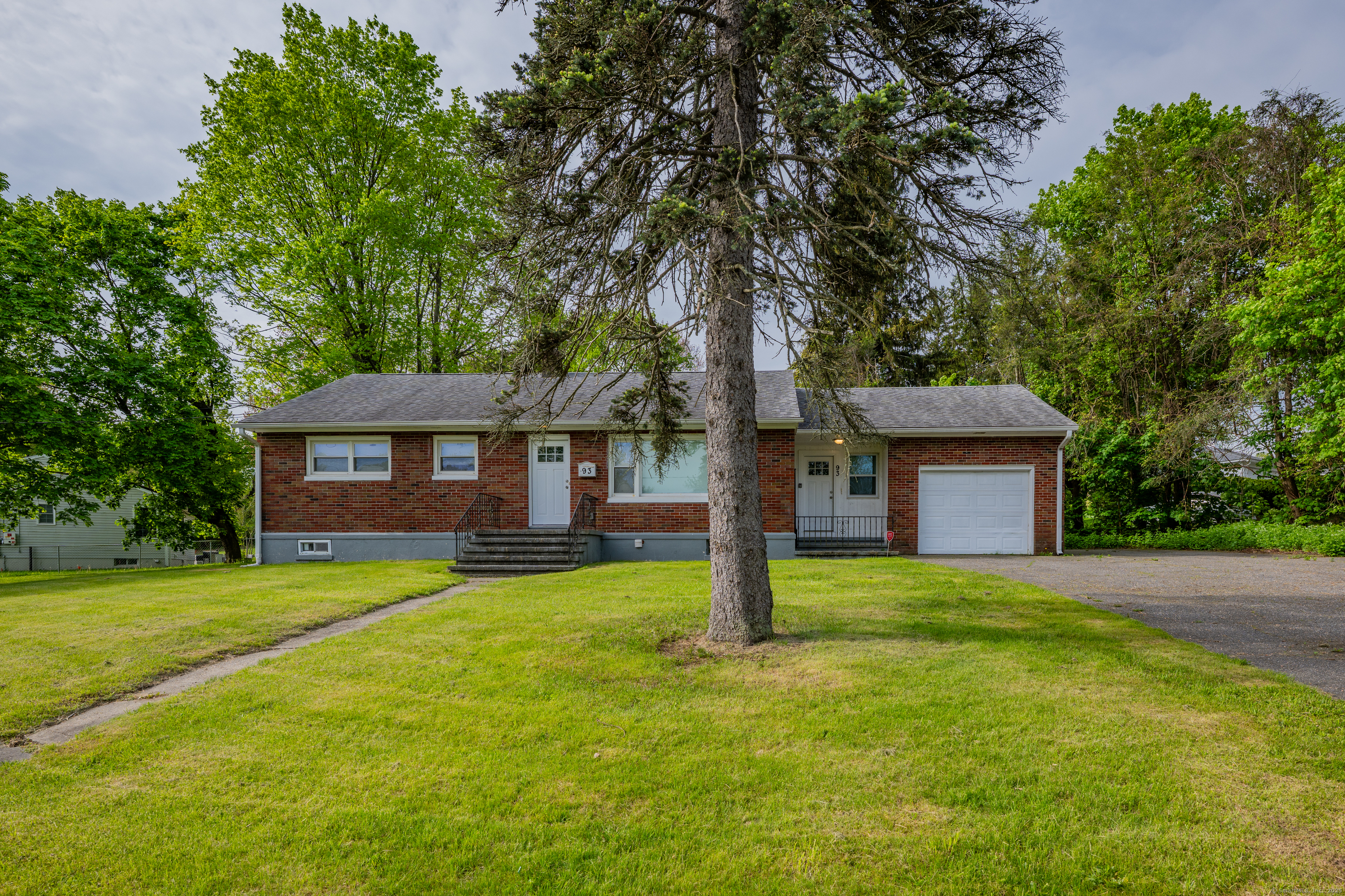 a front view of a house with yard and tree