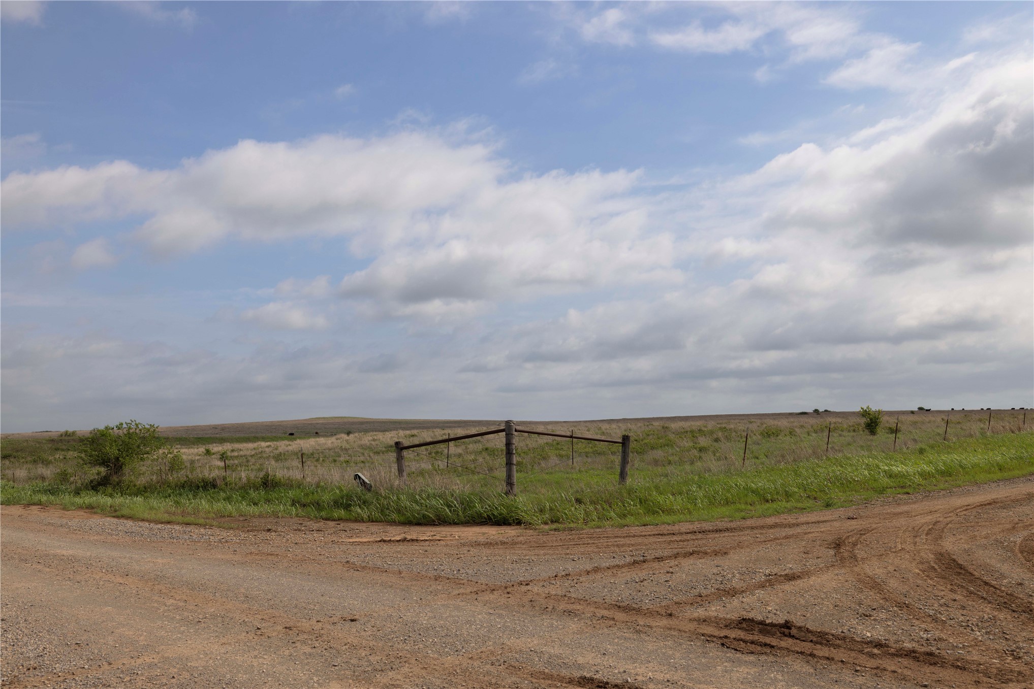 42 East 4500 Road Morrison, OK 73061 - Photo 11 of 37 Expansive rural landscape featuring a dirt road intersecting with a gravel road, a wooden fence line, and open pastureland with scattered trees