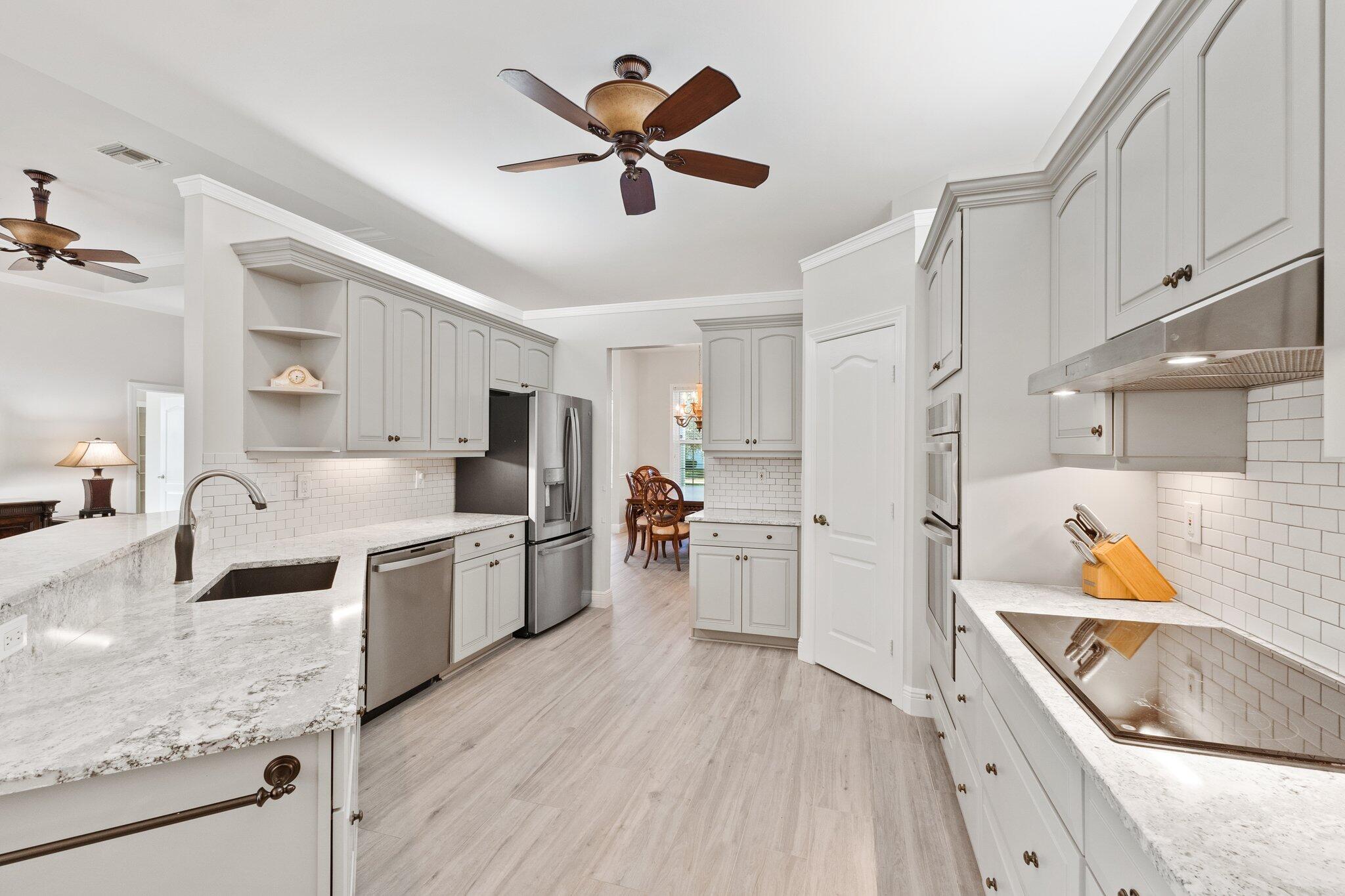 1680 Southeast Cypress Glen Way Stuart, FL 34997 - Photo 23 of 76 a kitchen with stainless steel appliances granite countertop a sink dishwasher stove and refrigerator with wooden floor