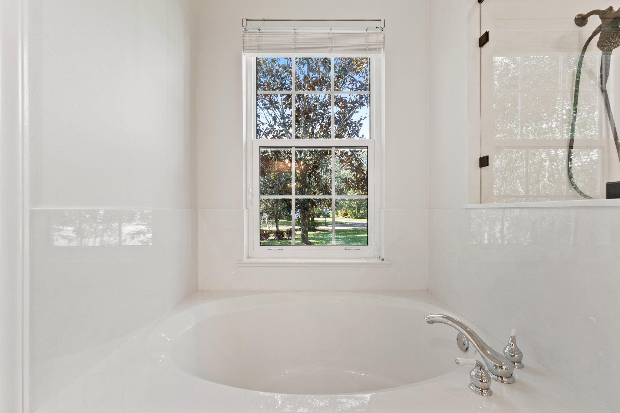 1680 Southeast Cypress Glen Way Stuart, FL 34997 - Photo 47 of 76 a white bath tub sitting in a bathroom next to a window