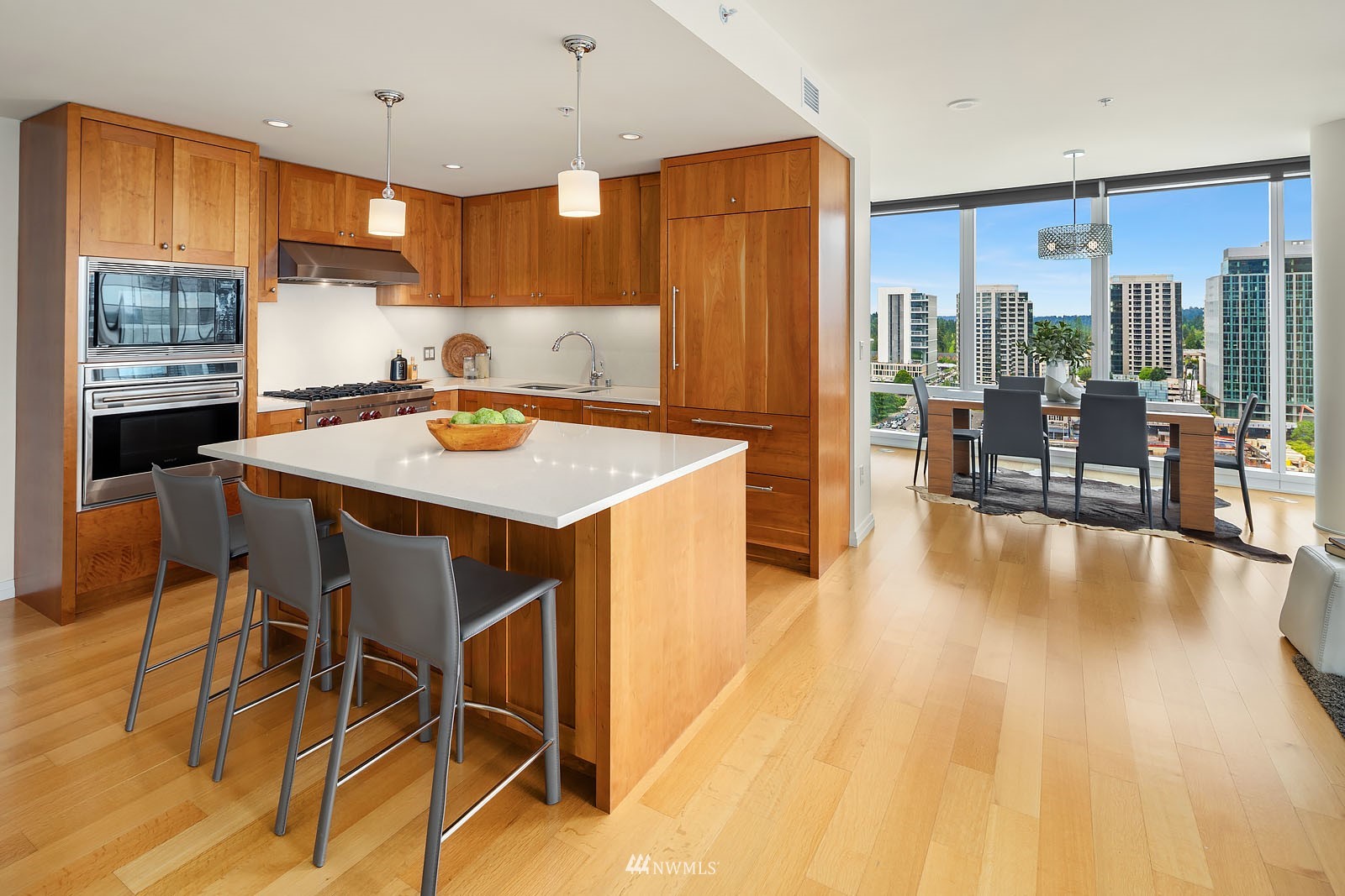 a kitchen with stainless steel appliances granite countertop a stove a refrigerator a kitchen island a dining table and chairs with wooden floor