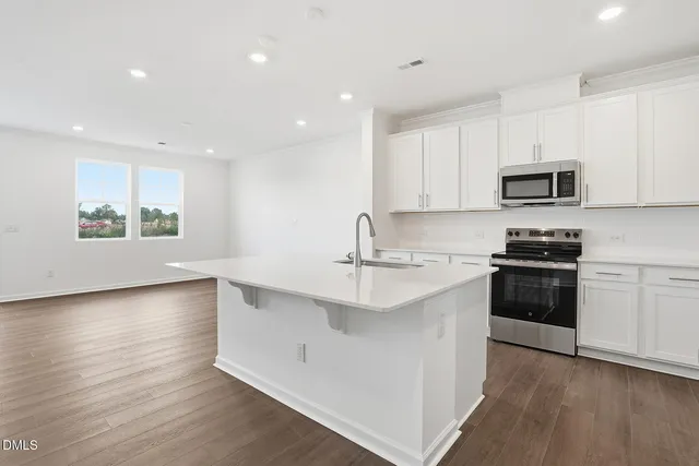 a kitchen with granite countertop a stove a sink and a microwave