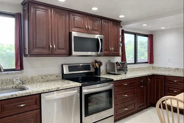a kitchen with granite countertop wooden cabinets and a stove top oven