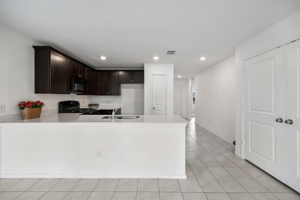 6038 Determine Lane Forney, TX 75126 - Photo 12 of 26 Kitchen featuring dark wood cabinetry, light-toned countertops, a stainless steel sink, and recessed lighting