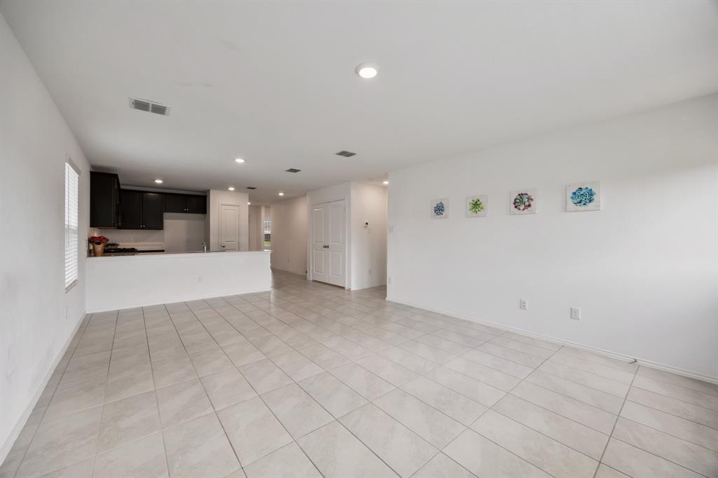 6038 Determine Lane Forney, TX 75126 - Photo 15 of 26 Open-concept living area featuring light-toned tile flooring, recessed lighting, and a partial wall separating a kitchen space