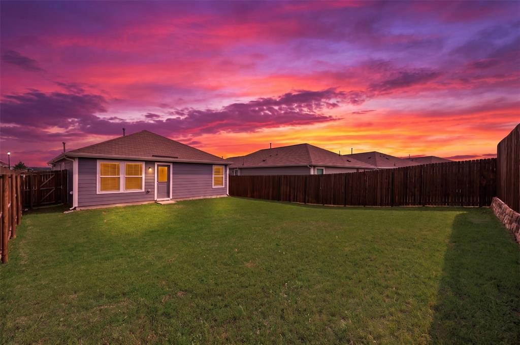 6038 Determine Lane Forney, TX 75126 - Photo 22 of 26 Expansive fenced backyard featuring a level lawn, privacy fencing, and a stone retaining wall