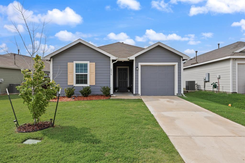 6038 Determine Lane Forney, TX 75126 - Photo 3 of 26 Contemporary single-story home featuring gray siding, a prominent attached garage with a matching door, and a concrete driveway