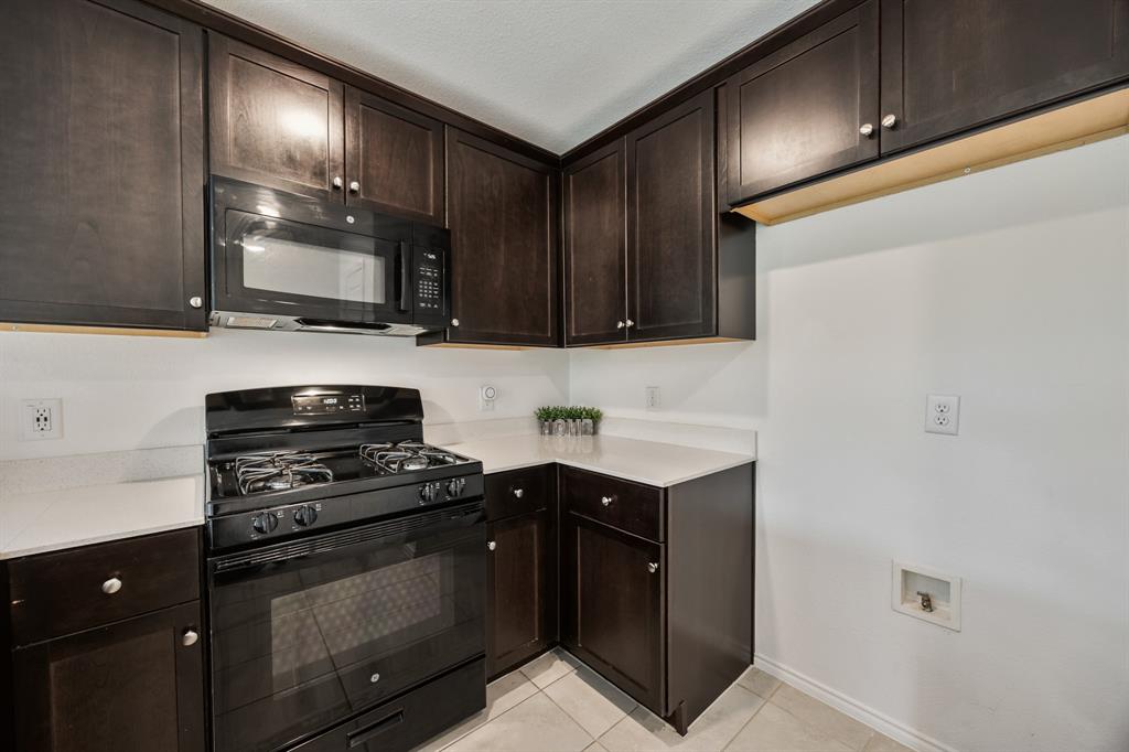 6038 Determine Lane Forney, TX 75126 - Photo 7 of 26 Kitchen featuring dark wood cabinetry, light countertops, black gas range, and a built-in microwave