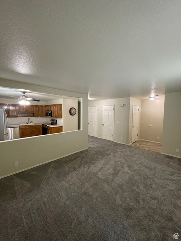 101 1501 Monroe, Unit 101 Ogden, UT 84404 - Photo 2 of 24 Unfurnished living room with a textured ceiling, dark carpet, and a ceiling fan