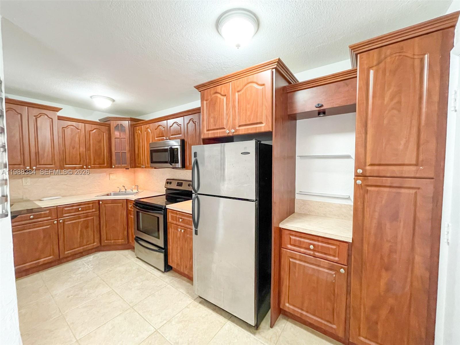 4450 Southwest 67th Avenue, Unit I Miami, FL 33155 - Photo 2 of 12 a kitchen with granite countertop stainless steel appliances and refrigerator