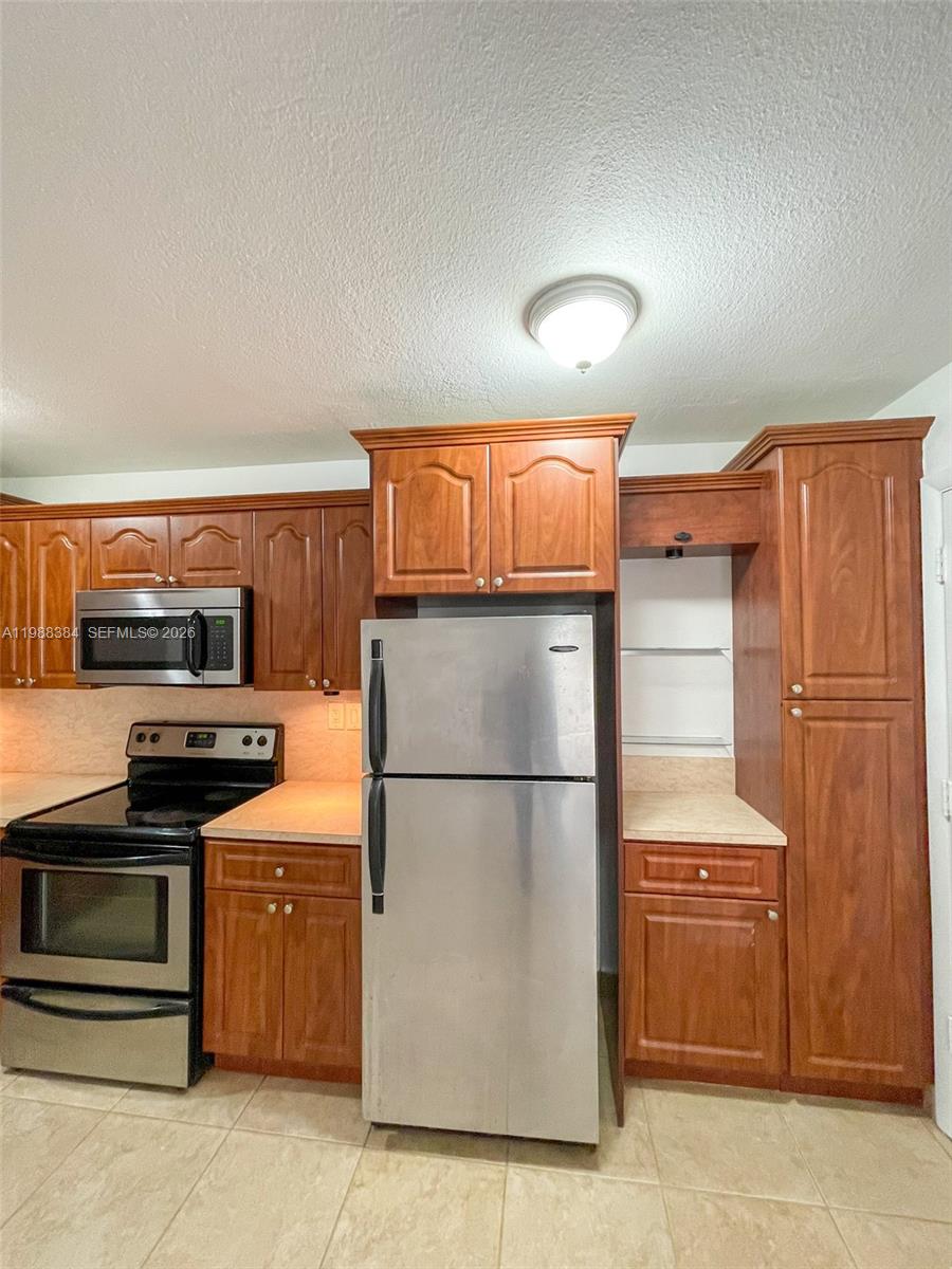 4450 Southwest 67th Avenue, Unit I Miami, FL 33155 - Photo 4 of 12 a kitchen with stainless steel appliances granite countertop a refrigerator stove and sink