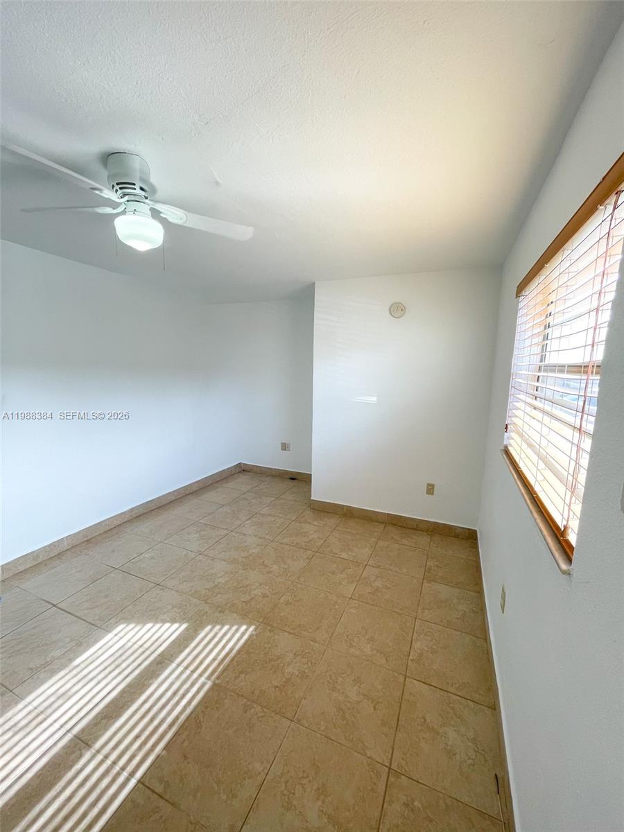 4450 Southwest 67th Avenue, Unit I Miami, FL 33155 - Photo 9 of 12 an empty room with windows and ceiling fan