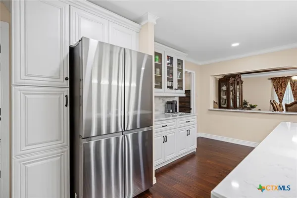 a kitchen with stainless steel appliances kitchen island granite countertop a table chairs refrigerator and microwave