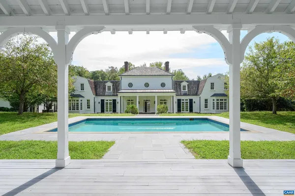 a view of a big house with a big yard and large trees