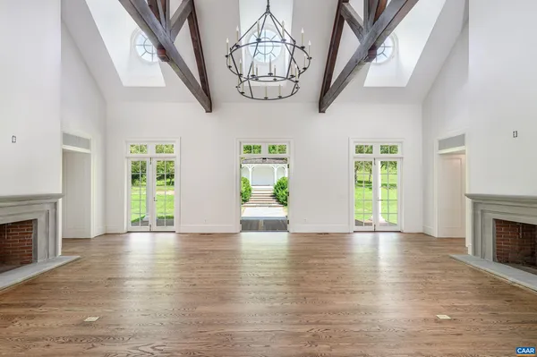 a view of an empty room with wooden floor fireplace and a window