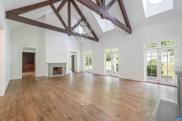 a view of an empty room with wooden floor a ceiling fan and windows