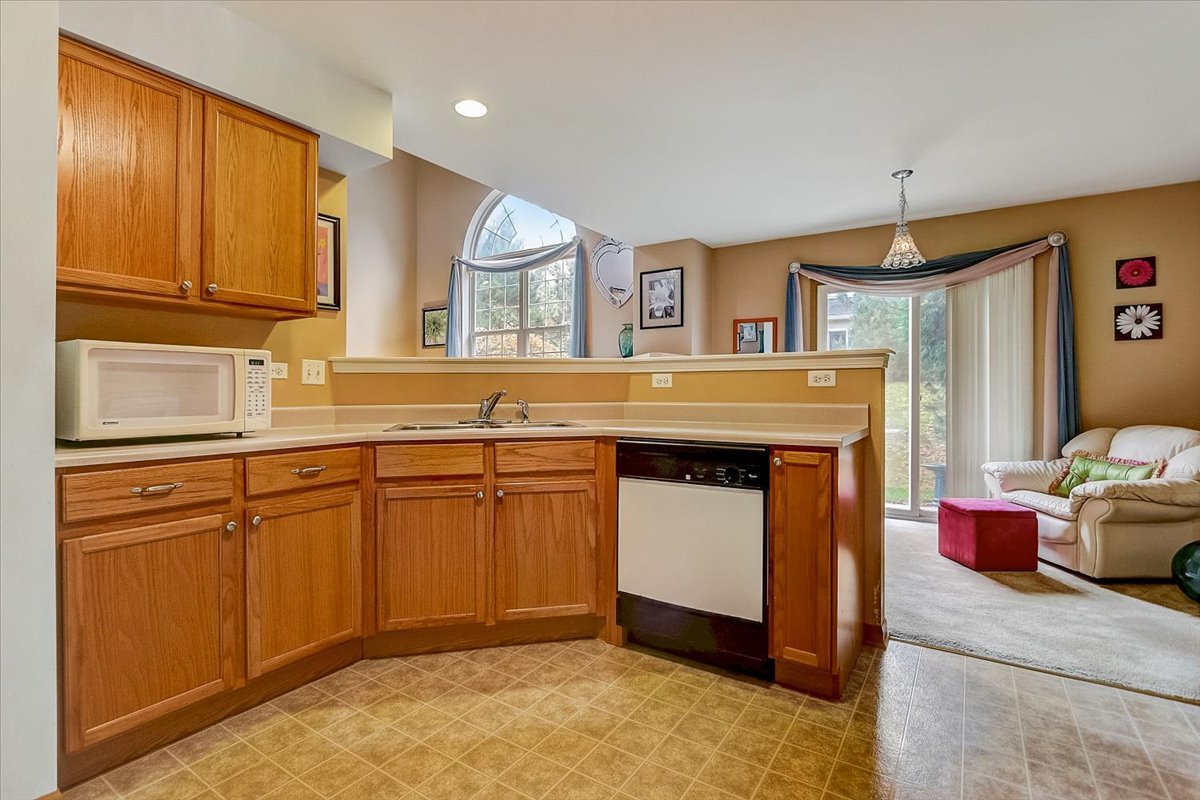63 Rolling Oaks Road, Unit B Sugar Grove, IL 60554 - Photo 10 of 23 a kitchen with stainless steel appliances granite countertop a stove a sink and a refrigerator with wooden floor