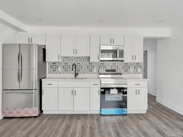 a kitchen with stainless steel appliances white cabinets and a refrigerator