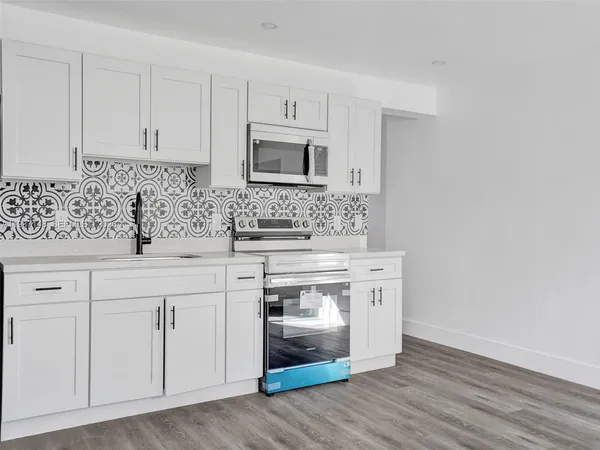 a kitchen with white cabinets and sink