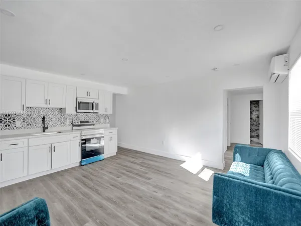 a kitchen with stainless steel appliances a stove top oven and white wooden cabinets