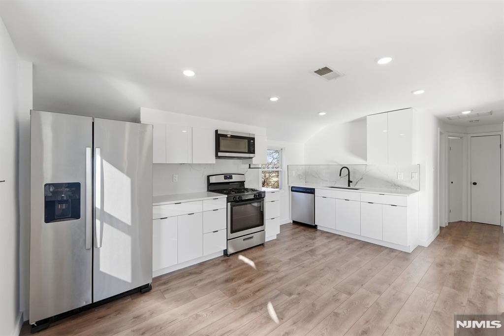 73 MacArthur Avenue Lodi, NJ 07644 - Photo 21 of 46 a kitchen with white cabinets and stainless steel appliances